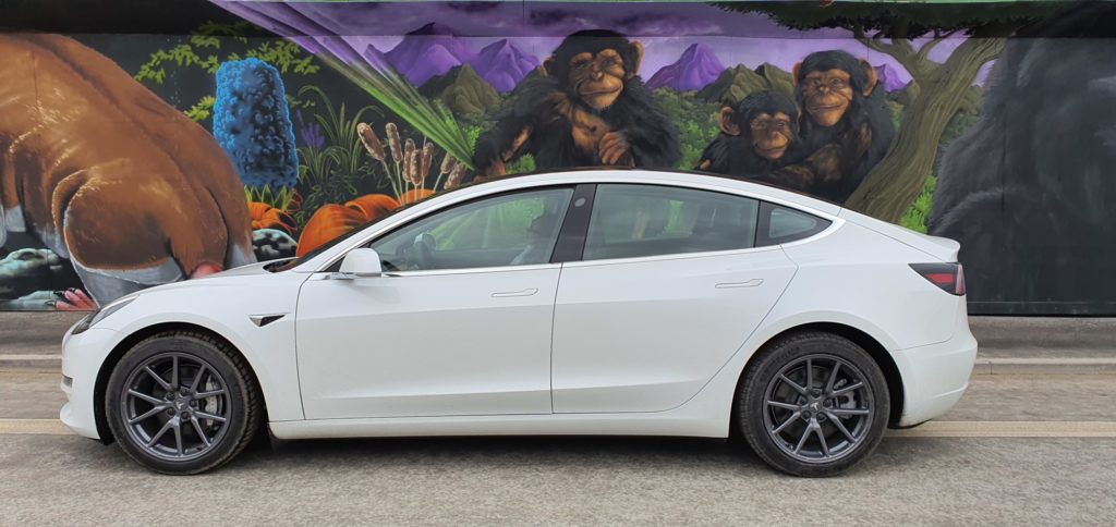 Hvid Tesla Model 3 foran grafittigalleri i Københavns Sydhavn